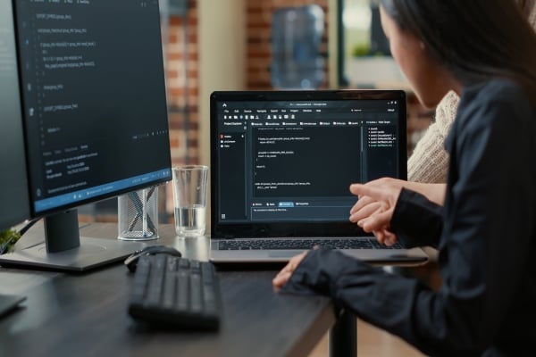 team-programmers-talking-about-algorithm-running-laptop-screen-pointing-source-code-while-sitting-desk-software-developers-collaborating-data